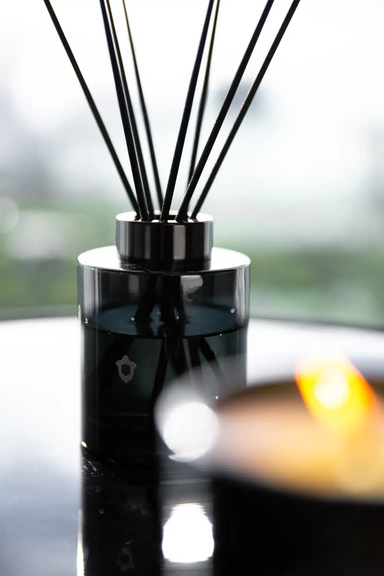 Somuti reed diffuser beside a softly lit scented candle
